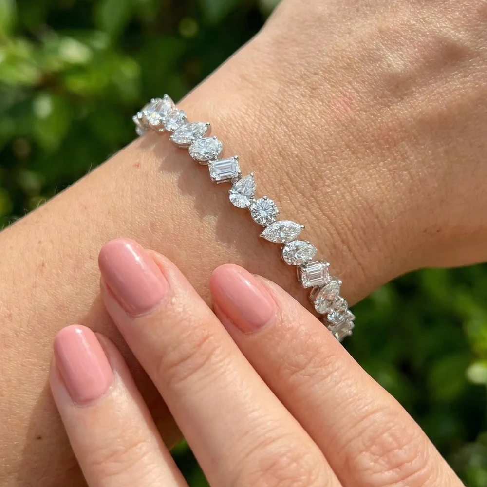A mixed-shape lab-grown diamond tennis bracelet on a woman’s wrist outdoors in the sun