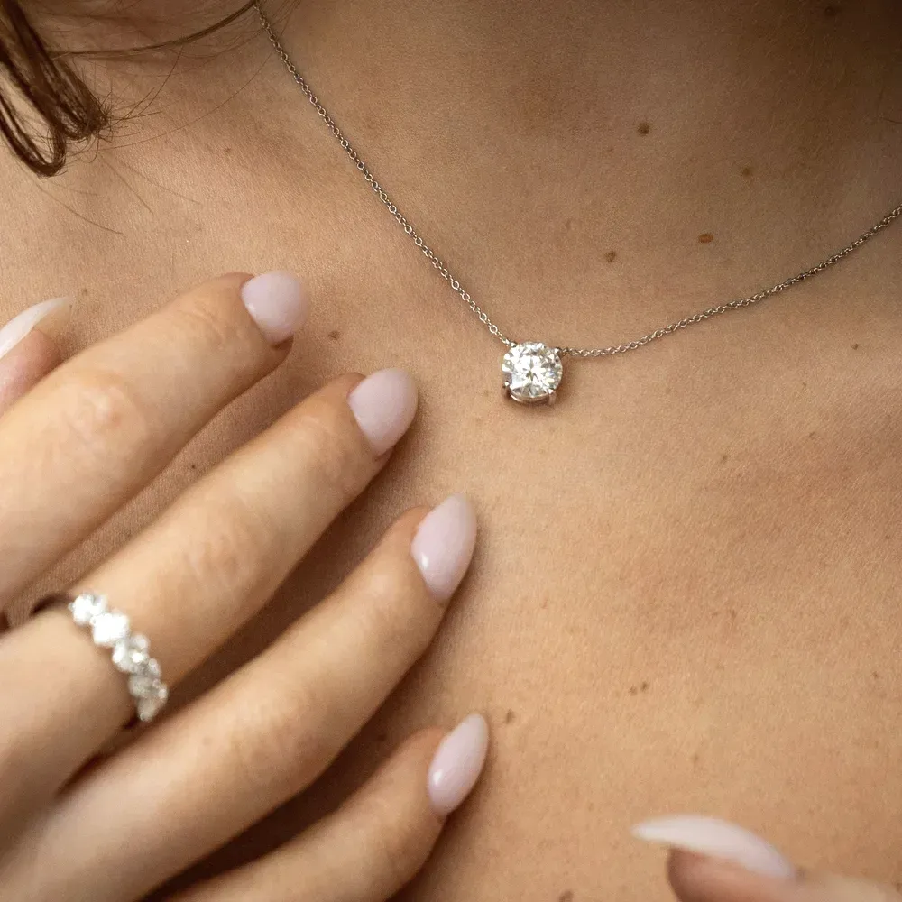 A cushion-cut lab-grown diamond solitaire necklace worn with a diamond band