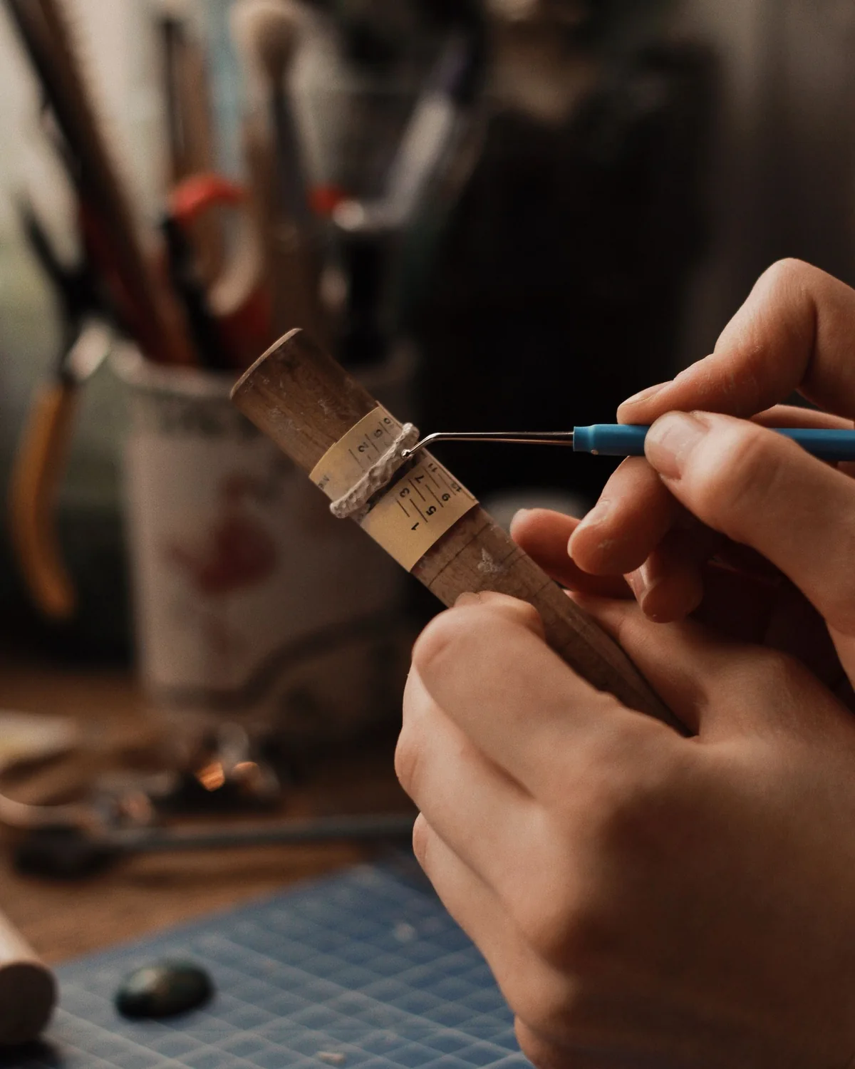 A jeweler shaping a ring on a wooden mandrel at the workbench