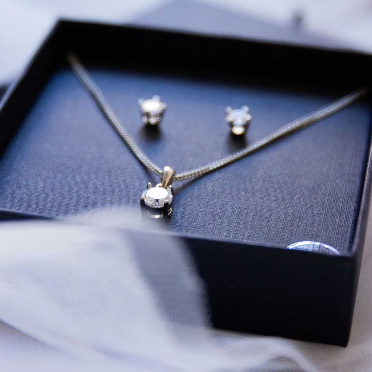 A lab-grown diamond solitaire pendant and matching stud earrings in a navy gift box