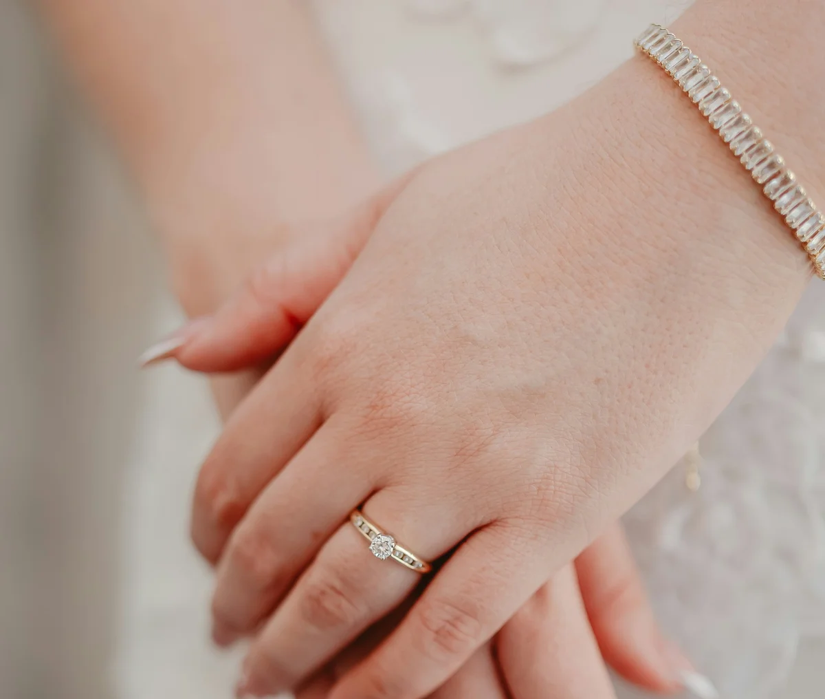 A bride’s hands wearing a baguette lab-grown diamond tennis bracelet and a diamond engagement ring