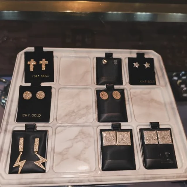 Gold cross, star, lightning bolt and square stud earrings on a display tray