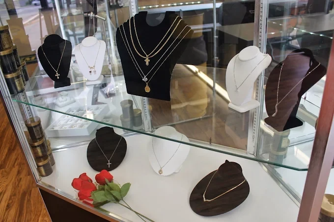 Gold chains and pendant necklaces on display busts inside a glass case at The Money Vault